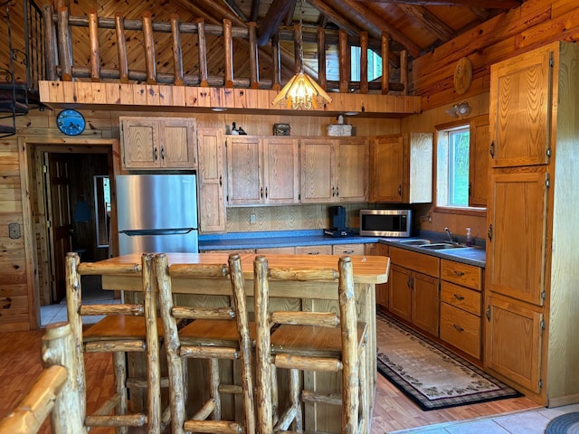 kitchen featuring wood walls, appliances with stainless steel finishes, sink, and light hardwood / wood-style flooring