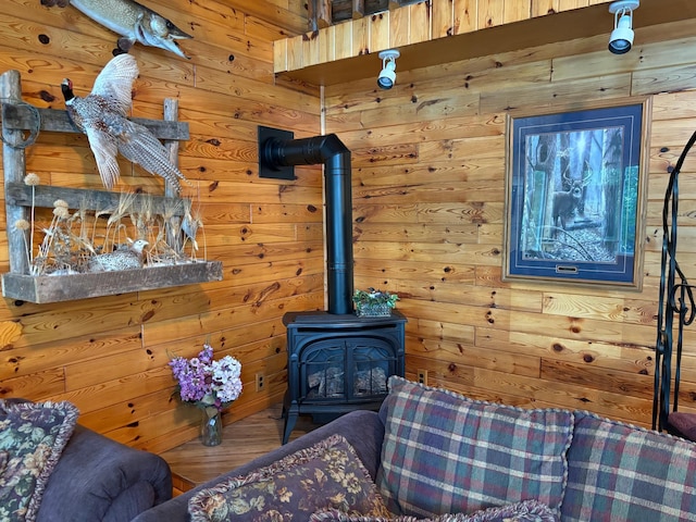 living room with wood-type flooring, a wood stove, and wooden walls