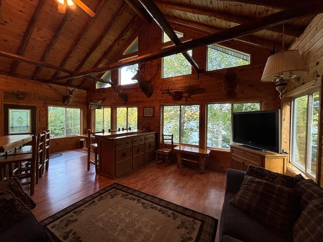 living room featuring a wealth of natural light, ceiling fan, wood walls, and hardwood / wood-style flooring