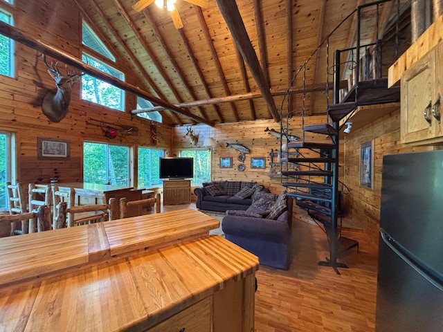 kitchen featuring high vaulted ceiling, wood walls, ceiling fan, and fridge