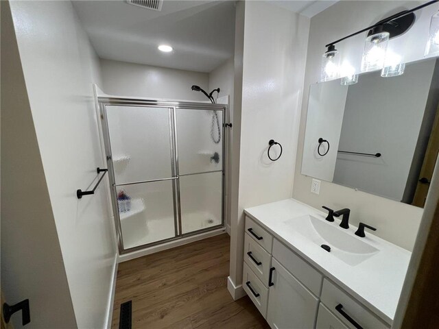 bathroom featuring vanity, hardwood / wood-style flooring, and a shower with shower door