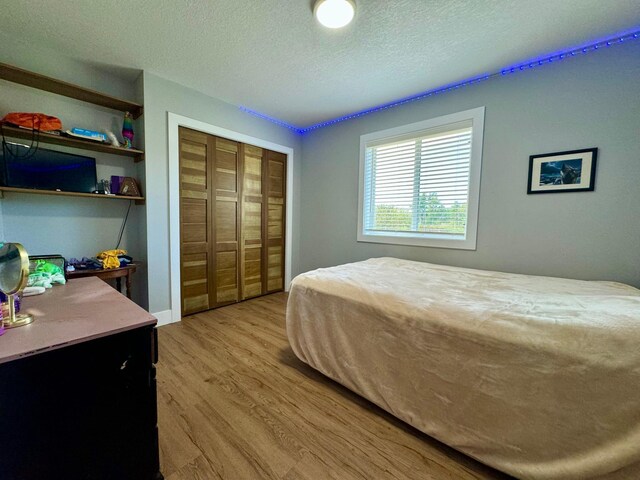 bedroom with a textured ceiling, a closet, and wood-type flooring