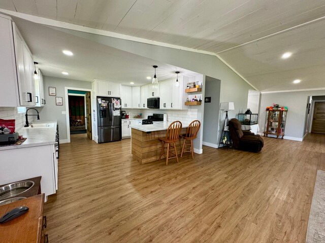 kitchen with white cabinets, light hardwood / wood-style flooring, sink, lofted ceiling, and black appliances