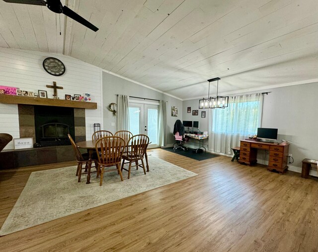 dining area with lofted ceiling, a wealth of natural light, a tiled fireplace, and french doors