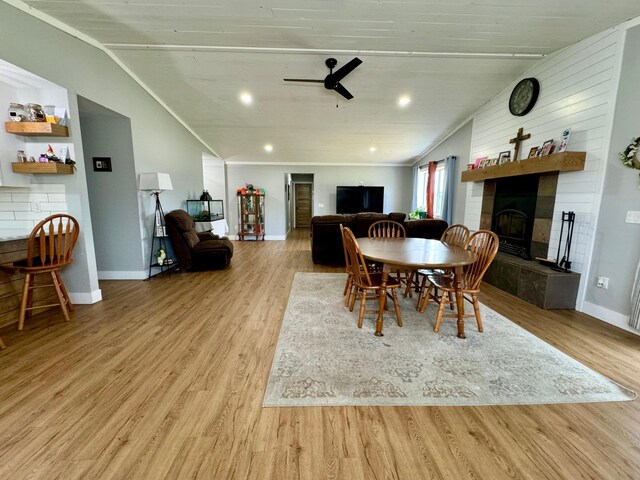 dining space with ceiling fan, a tile fireplace, light hardwood / wood-style floors, and crown molding