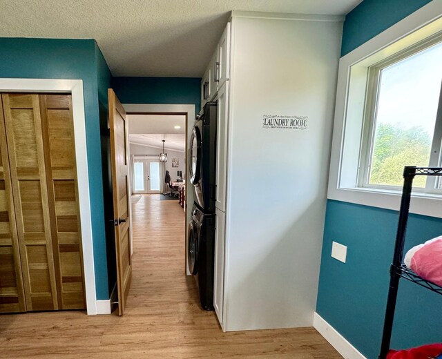 corridor featuring a textured ceiling, french doors, and light hardwood / wood-style floors