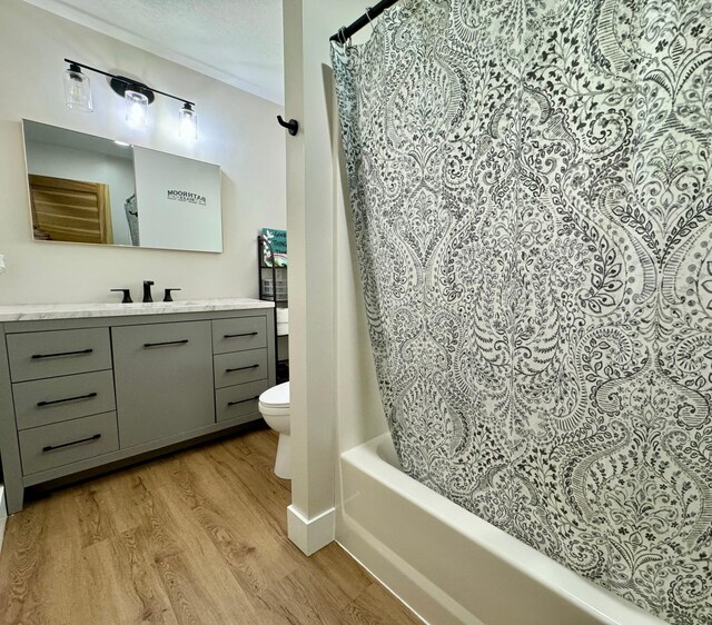 full bathroom featuring toilet, hardwood / wood-style floors, vanity, a textured ceiling, and shower / bath combination with curtain