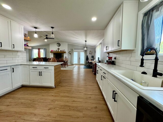 kitchen with a healthy amount of sunlight, vaulted ceiling, light wood-type flooring, and white cabinets