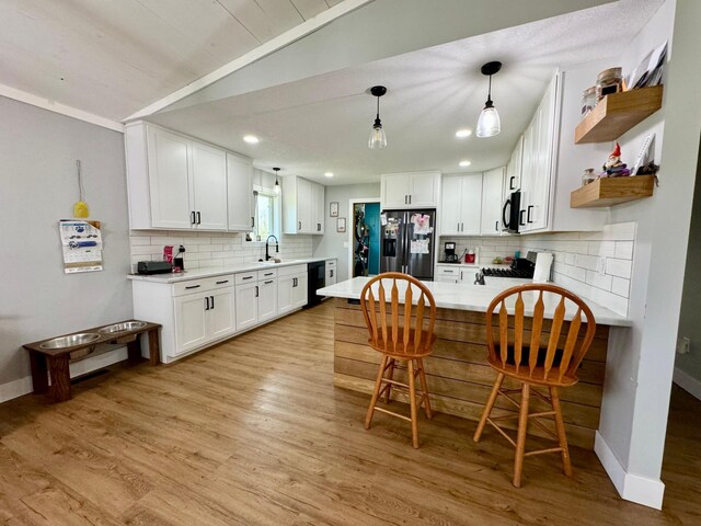 kitchen with stainless steel appliances, tasteful backsplash, white cabinets, and light hardwood / wood-style floors