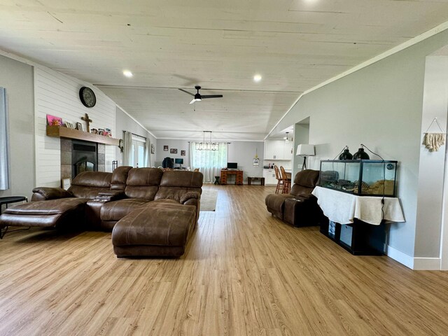 living room with light wood-type flooring, ornamental molding, wood walls, ceiling fan, and vaulted ceiling