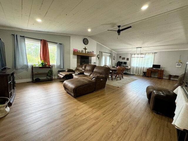 living room featuring ceiling fan with notable chandelier, a fireplace, light hardwood / wood-style flooring, ornamental molding, and lofted ceiling