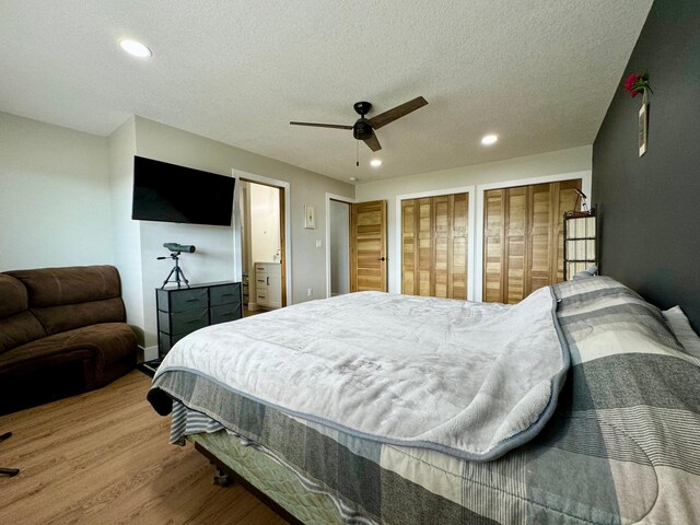 bedroom with a textured ceiling, wood-type flooring, two closets, and ceiling fan