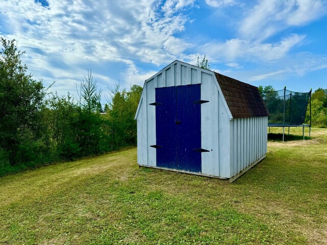 view of outbuilding with a lawn and a trampoline