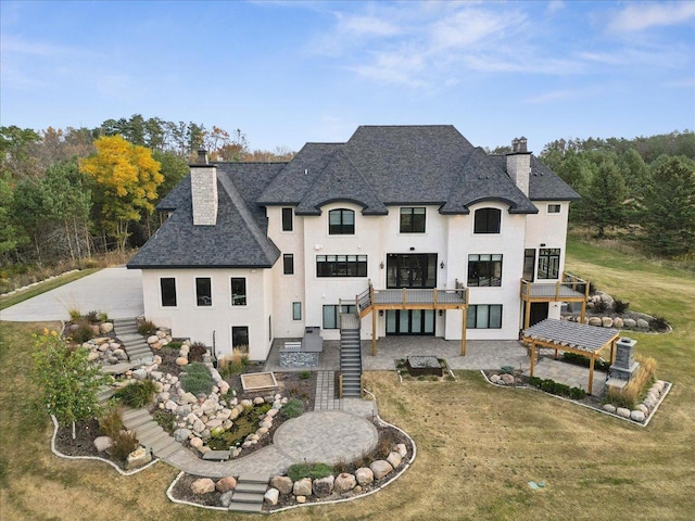 rear view of property with stairs, stucco siding, a chimney, a yard, and a patio area