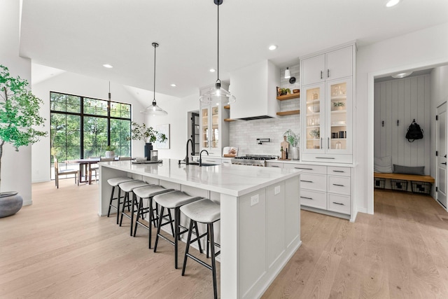 kitchen with decorative light fixtures, a spacious island, light hardwood / wood-style floors, and white cabinetry