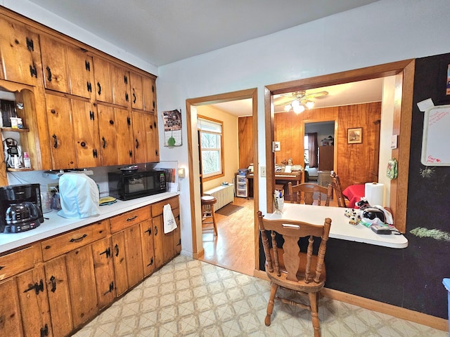 kitchen featuring radiator, ceiling fan, and wooden walls