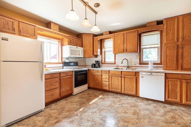 kitchen featuring pendant lighting, plenty of natural light, sink, and white appliances