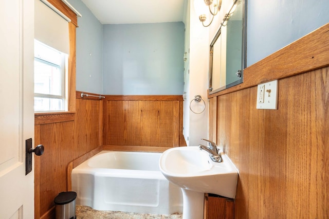 bathroom featuring wood walls and a washtub