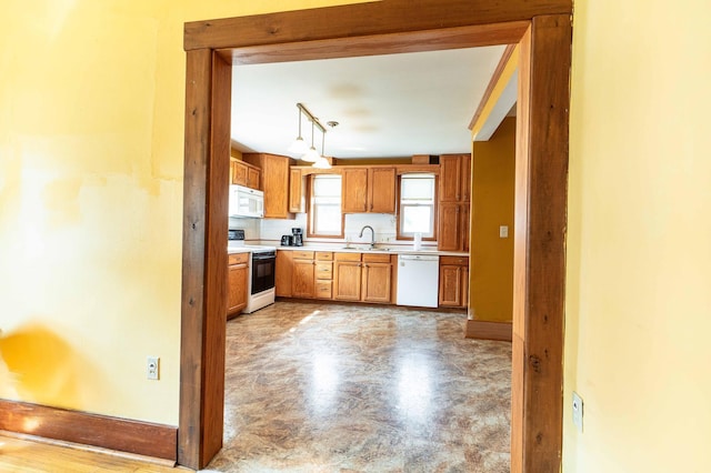 kitchen featuring hanging light fixtures, white appliances, sink, and rail lighting