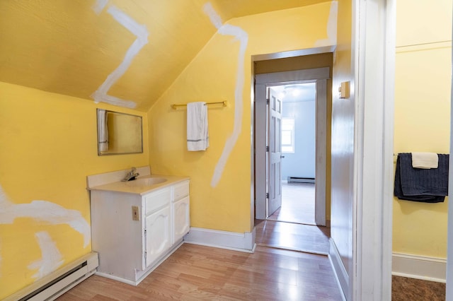 bathroom featuring hardwood / wood-style flooring, vanity, vaulted ceiling, and a baseboard radiator