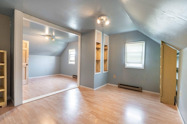 bonus room featuring vaulted ceiling, light hardwood / wood-style floors, and baseboard heating