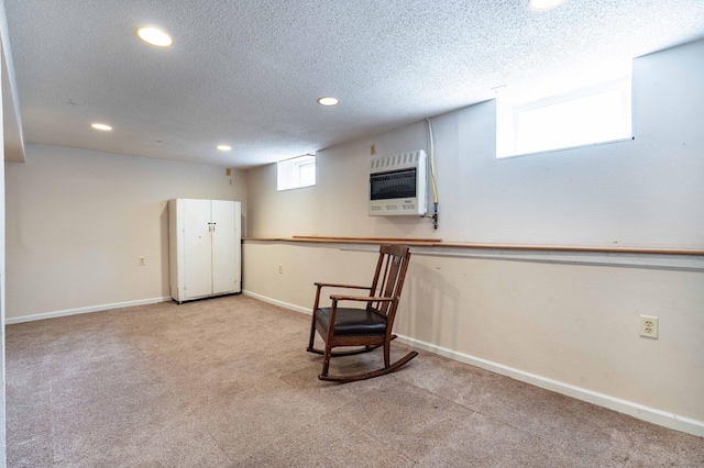 sitting room with light carpet, heating unit, and a textured ceiling