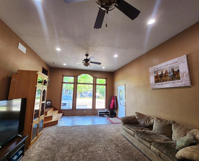 carpeted living room featuring ceiling fan and a textured ceiling