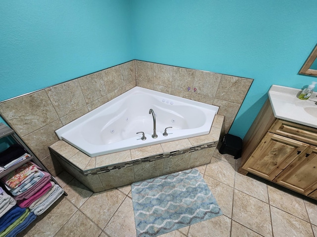 bathroom featuring tile patterned flooring, tiled bath, and vanity