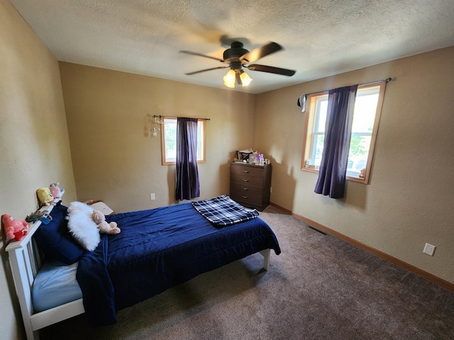 bedroom with ceiling fan, multiple windows, carpet floors, and a textured ceiling