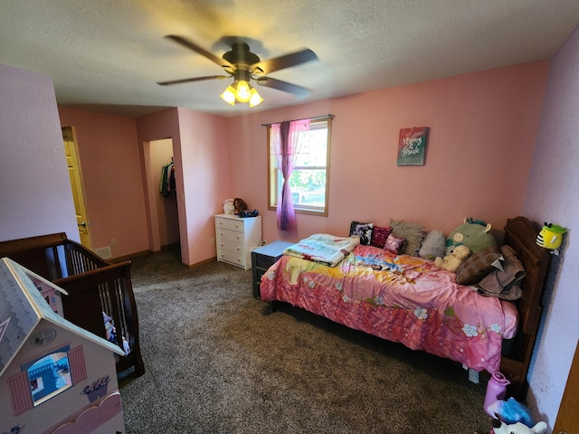 bedroom with a textured ceiling, dark carpet, and ceiling fan