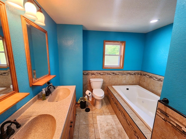 bathroom with tiled bath, vanity, a textured ceiling, toilet, and tile patterned floors