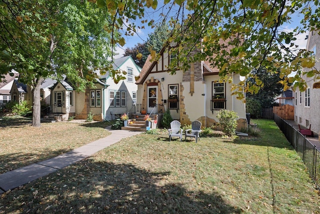 view of front facade with stucco siding, a front lawn, and fence