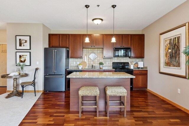 kitchen with backsplash, a center island, a kitchen bar, black appliances, and dark wood-style flooring