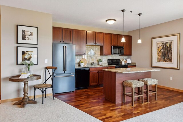 kitchen with a kitchen island, dark wood finished floors, a breakfast bar, decorative backsplash, and black appliances