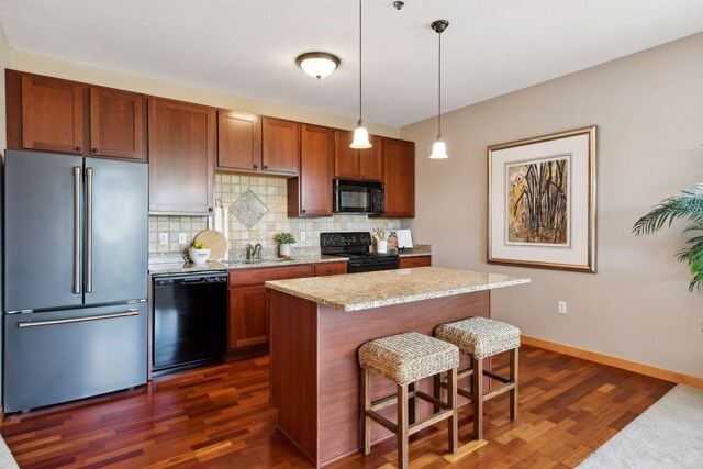 kitchen featuring black appliances, a breakfast bar, dark wood finished floors, decorative backsplash, and baseboards