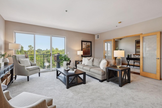 living area featuring visible vents, light carpet, and french doors