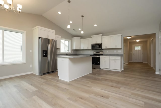 kitchen with a kitchen island, stainless steel appliances, decorative light fixtures, and light hardwood / wood-style flooring