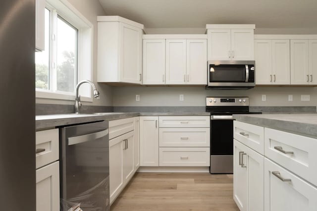 kitchen featuring stainless steel appliances, light hardwood / wood-style floors, white cabinetry, and sink