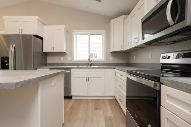 kitchen with stainless steel appliances, sink, vaulted ceiling, and white cabinets