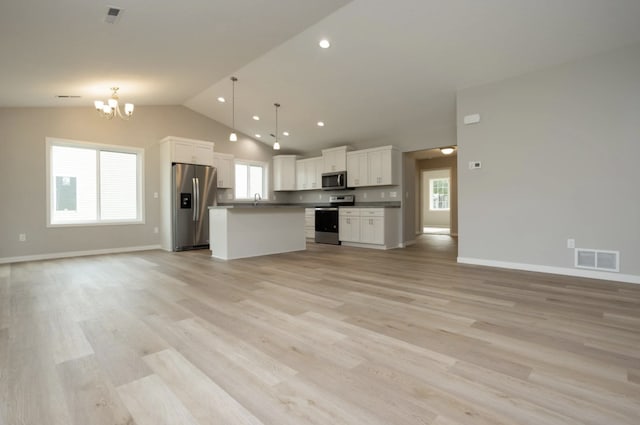 kitchen with stainless steel appliances, a center island, hanging light fixtures, white cabinets, and light hardwood / wood-style floors