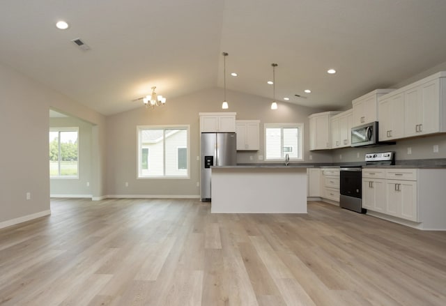 kitchen featuring light wood-type flooring, appliances with stainless steel finishes, hanging light fixtures, and white cabinetry