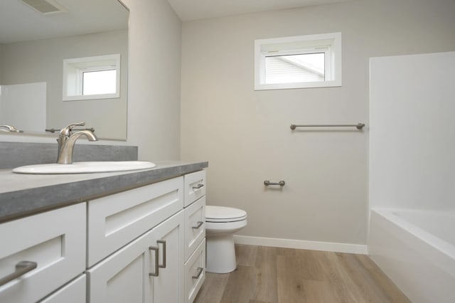 bathroom with a bathtub, toilet, hardwood / wood-style flooring, and vanity