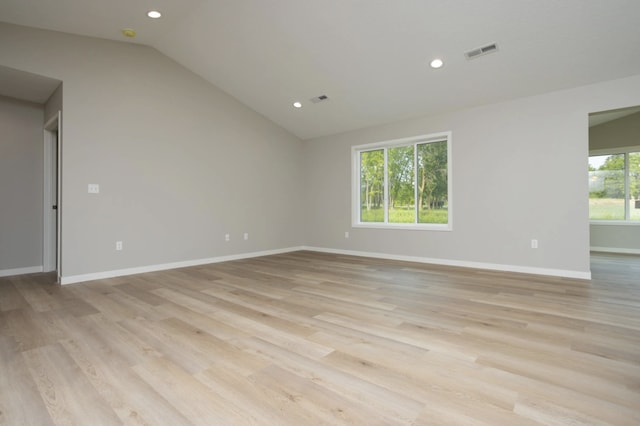 empty room with light wood-type flooring and vaulted ceiling