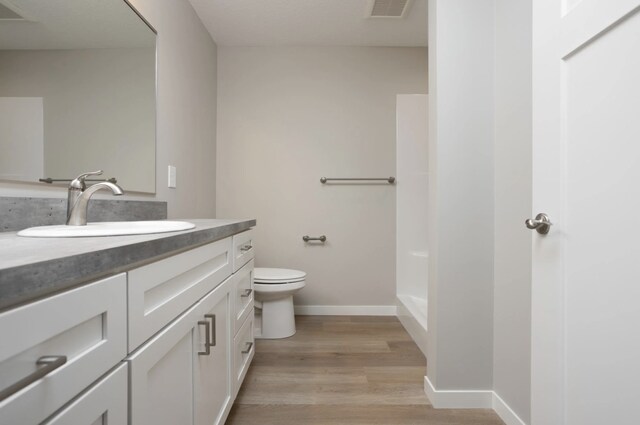 bathroom featuring vanity, toilet, hardwood / wood-style floors, and a shower