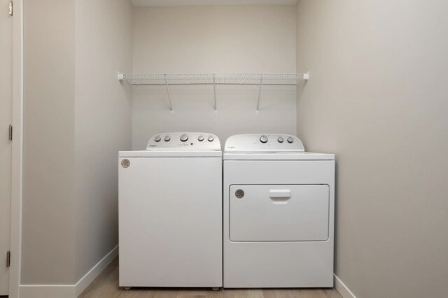 clothes washing area featuring separate washer and dryer and light hardwood / wood-style flooring