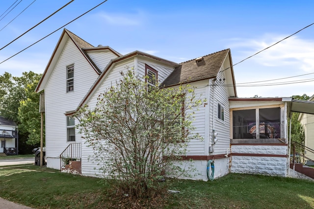 view of home's exterior featuring a sunroom and a yard