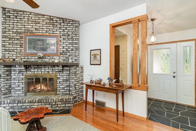 interior space with vaulted ceiling, a brick fireplace, and wood-type flooring