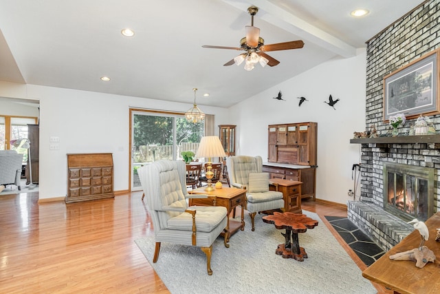 living room featuring light hardwood / wood-style floors, ceiling fan, vaulted ceiling with beams, and a brick fireplace