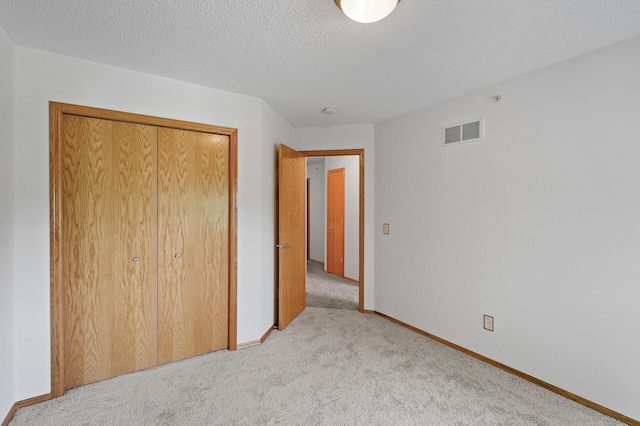 unfurnished bedroom with light carpet, a closet, and a textured ceiling