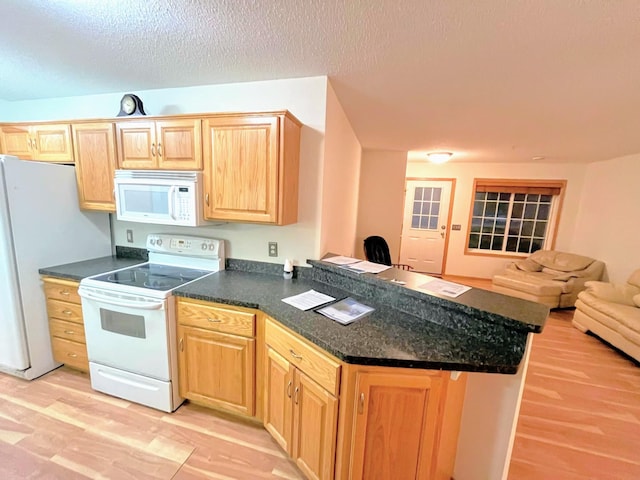 kitchen featuring kitchen peninsula, white appliances, a textured ceiling, and light hardwood / wood-style floors